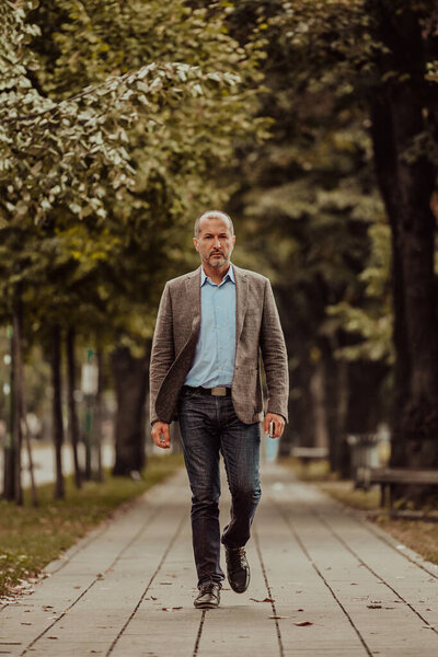 Focused businessman in a suit walking in the park. High quality photo