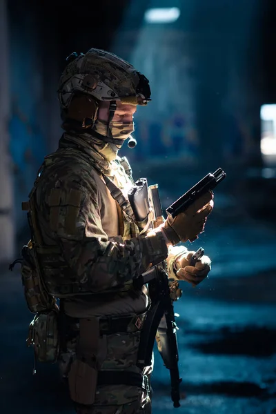 Soldier of army elite forces, special security service fighter with hidden behind mask and glasses face, in helmet and load carriage system, aiming with service pistol low key. High quality photo