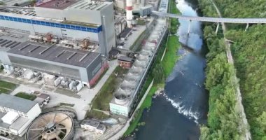 Mavi nehrin yanında iki yüksek soğutmalı kuleli kömür santralinin insansız hava aracı görüntüsü. Bacalardan çıkan duman ve güç üreten türbinlerden çıkan buhar. Yüksek kalite 4k görüntü
