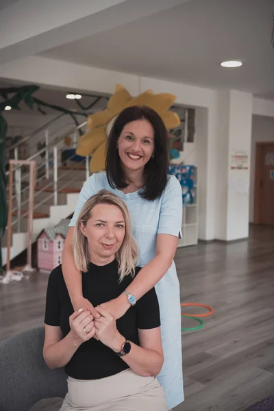 Portrait Two Hugging Female Teachers Preschool Institution Background Classrooms High — Stock Photo, Image