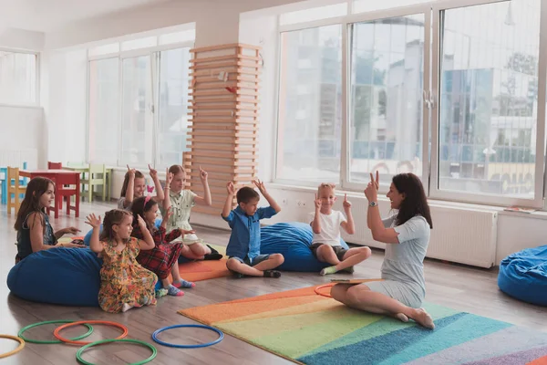 Een Gelukkige Vrouwelijke Leraar Zitten Spelen Hand Games Met Een — Stockfoto