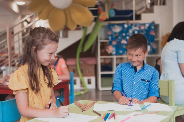 Niedliche Mädchen Und Jungen Sitzen Und Zeichnen Zusammen Den Vorschuleinrichtungen — Stockfoto