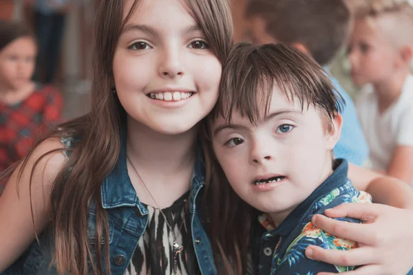 一个女孩和一个患有唐斯综合症的男孩抱在一起 在幼儿园呆着 高质量的照片 — 图库照片