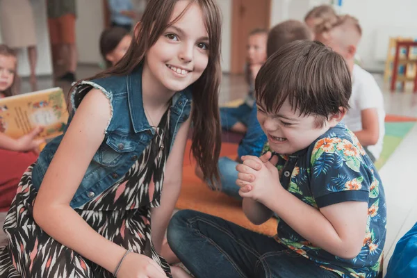 A girl and a boy with Downs syndrome in each others arms spend time together in a preschool institution. High quality photo