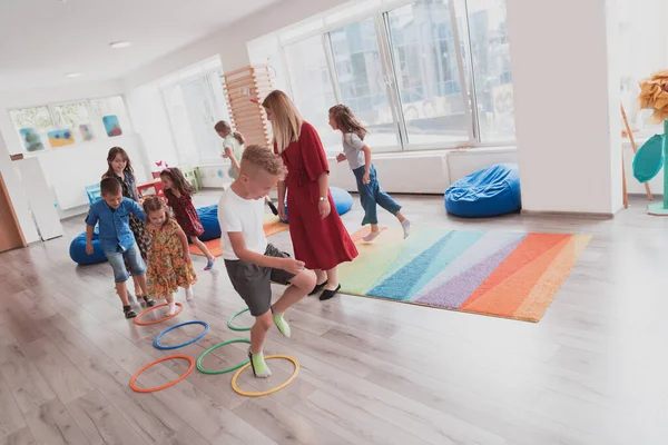 Små Förskolebarn Med Kvinnlig Lärare Golvet Inomhus Klassrummet Motionerar Hoppar — Stockfoto