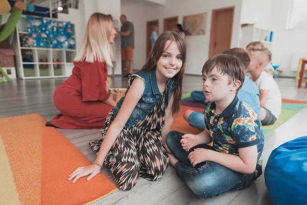 一个女孩和一个患有唐斯综合症的男孩抱在一起 在幼儿园呆着 高质量的照片 — 图库照片