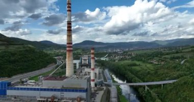 Mavi nehrin yanında iki yüksek soğutmalı kuleli kömür santralinin insansız hava aracı görüntüsü. Bacalardan çıkan duman ve güç üreten türbinlerden çıkan buhar. Yüksek kalite 4k görüntü