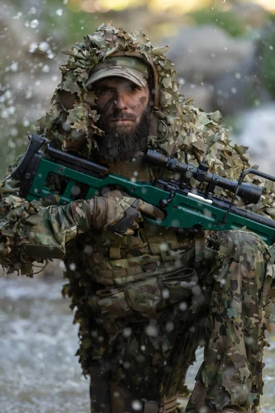カモフラージュスーツを着た軍人やエアソフトプレーヤーが川を忍び寄り 狙撃銃から側面や標的に狙いを定めている 高品質の写真 — ストック写真