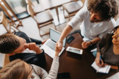 İş adamlarının resmi görüşü oturarak kahve içer ve verileri analiz eder. Masada dizüstü bilgisayarlar, grafikler, tabletler ve evraklar var. Yüksek kalite fotoğraf