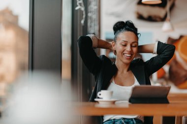 Kolları havada bir kafede oturan bir kadın iyi bir iş çıkardığını kutluyor. İş konsepti. Yüksek kalite fotoğraf