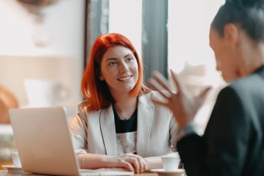Bir kafede masada oturan iki genç iş kadını. Kadın bilgisayar ekranında iş arkadaşı bilgilerini gösteriyor. Akıllı telefon kullanan, blog yazan bir kız. Takım çalışması, iş toplantıları. Yüksek kalite fotoğraf