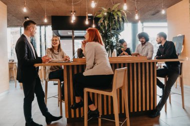 Bir grup arkadaş bir kafede takılıyor ve aralarında bir tablet var. Lokantada tablet kullanan mutlu gençler.
