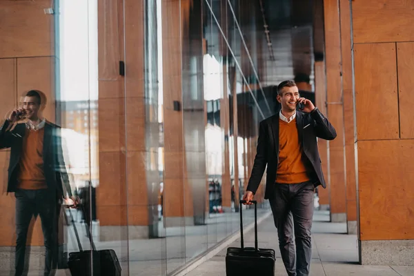 空港ターミナルに行く 街を歩き スーツケースを持ってコーヒーを飲み スマートフォンで話すビジネスマンの旅行者を確信しています 高品質の写真 — ストック写真