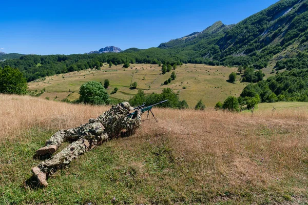 army soldier holding sniper rifle with scope and aiming in forest. war, army, technology and people concept. High quality photo