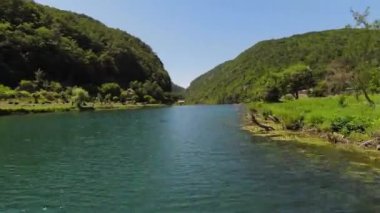 FPV Aerial doğal manzara nehri Una 'da Strbacki Buk şelalesiyle ağaçların altındaki yoğun yeşil ormanda uçma becerisini yakaladı. Yüksek kalite 4k görüntü