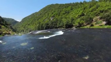 FPV Aerial doğal manzara nehri Una 'da Strbacki Buk şelalesiyle ağaçların altındaki yoğun yeşil ormanda uçma becerisini yakaladı. Yüksek kalite 4k görüntü