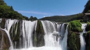 FPV Aerial doğal manzara nehri Una 'da Strbacki Buk şelalesiyle ağaçların altındaki yoğun yeşil ormanda uçma becerisini yakaladı. Yüksek kalite 4k görüntü