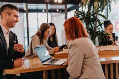 Bir grup arkadaş bir kafede takılıyor ve aralarında bir tablet var. Lokantada tablet kullanan mutlu gençler.