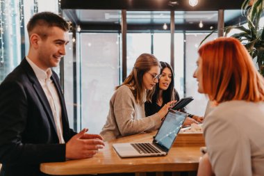 Bir grup arkadaş bir kafede takılıyor ve aralarında bir tablet var. Lokantada tablet kullanan mutlu gençler.