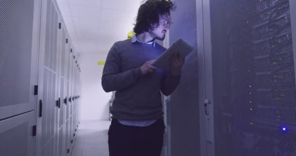 在现代云计算虚拟数据中心超级计算机的服务器室内从事平板计算机工作的It工程师或数据科学专家 穿着休闲装的嬉皮士穿着衣架走着 — 图库视频影像
