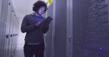 Modern bir sanal veri merkezi süperbilgisayarının sunucu odasında tablet bilgisayar üzerinde çalışan bilişim mühendisi ya da veri bilimci. Sıradan kıyafetler giyen hippi, askıda yürüyor.. 