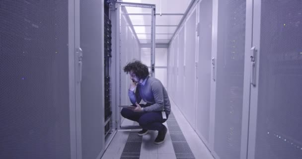 Itエンジニアやデータサイエンスの専門家は 現代のクラウドコンピューティング仮想データセンタースーパーコンピュータのサーバールームでタブレットコンピュータに取り組んでいます ラック廊下で働くカジュアル服を身に着けているヒップスター — ストック動画