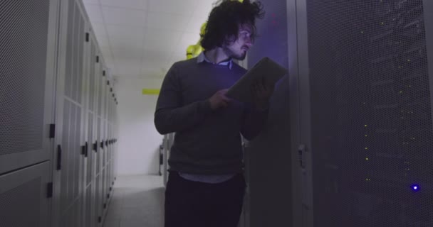 在现代云计算虚拟数据中心超级计算机的服务器室内从事平板计算机工作的It工程师或数据科学专家 穿着休闲装的嬉皮士穿着衣架走着 — 图库视频影像