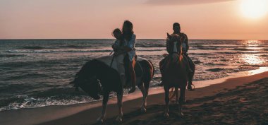 Aile kumlu bir sahilde birlikte ata binerken çocuklarıyla vakit geçirir. Seçici odaklanma. Yüksek kalite fotoğraf