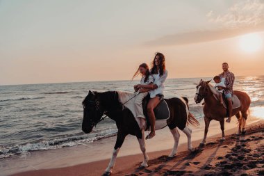 Aile kumlu bir sahilde birlikte ata binerken çocuklarıyla vakit geçirir. Seçici odaklanma. Yüksek kalite fotoğraf