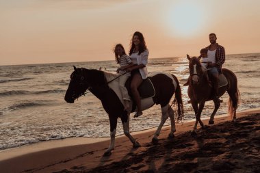 Aile kumlu bir sahilde birlikte ata binerken çocuklarıyla vakit geçirir. Seçici odaklanma. Yüksek kalite fotoğraf