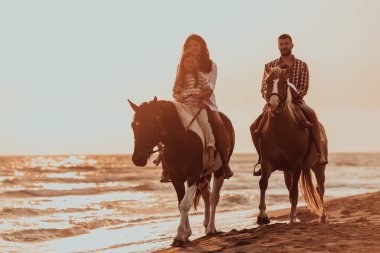 The family spends time with their children while riding horses together on a sandy beach. Selective focus. High quality photo