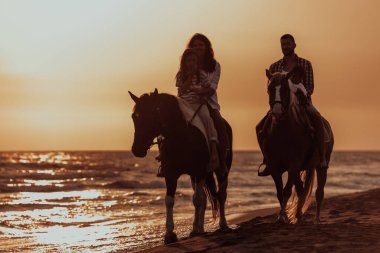 Aile kumlu bir sahilde birlikte ata binerken çocuklarıyla vakit geçirir. Seçici odaklanma. Yüksek kalite fotoğraf