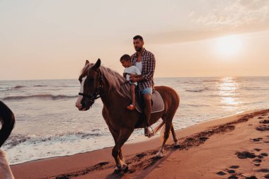 Baba ve oğul deniz kenarında at sürmekten hoşlanırlar. Seçici odaklanma. Yüksek kalite fotoğraf