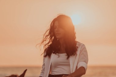 Yaz kıyafetleri içinde bir kadın gün batımında kumlu güzel bir sahilde ata binmekten hoşlanır. Seçici odaklanma. Yüksek kalite fotoğraf