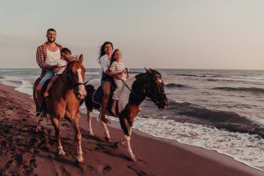 Aile kumlu bir sahilde birlikte ata binerken çocuklarıyla vakit geçirir. Seçici odaklanma. Yüksek kalite fotoğraf