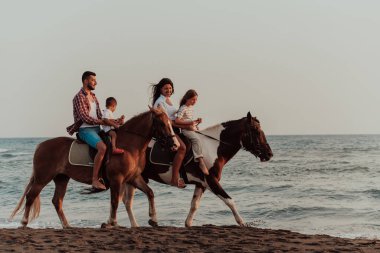 Aile kumlu bir sahilde birlikte ata binerken çocuklarıyla vakit geçirir. Seçici odaklanma. Yüksek kalite fotoğraf