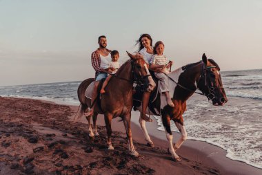 Aile kumlu bir sahilde birlikte ata binerken çocuklarıyla vakit geçirir. Seçici odaklanma. Yüksek kalite fotoğraf