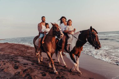 Aile kumlu bir sahilde birlikte ata binerken çocuklarıyla vakit geçirir. Seçici odaklanma. Yüksek kalite fotoğraf