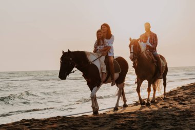 Aile kumlu bir sahilde birlikte ata binerken çocuklarıyla vakit geçirir. Seçici odaklanma. Yüksek kalite fotoğraf