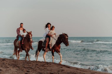 Aile kumlu bir sahilde birlikte ata binerken çocuklarıyla vakit geçirir. Seçici odaklanma. Yüksek kalite fotoğraf