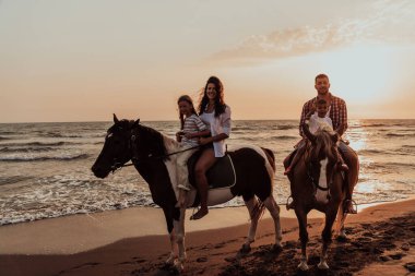 Aile kumlu bir sahilde birlikte ata binerken çocuklarıyla vakit geçirir. Seçici odaklanma. Yüksek kalite fotoğraf