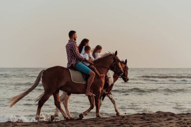 Aile kumlu bir sahilde birlikte ata binerken çocuklarıyla vakit geçirir. Seçici odaklanma. Yüksek kalite fotoğraf