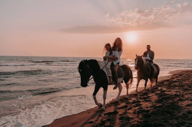 Aile kumlu bir sahilde birlikte ata binerken çocuklarıyla vakit geçirir. Seçici odaklanma. Yüksek kalite fotoğraf