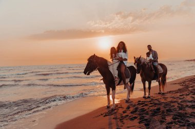 Aile kumlu bir sahilde birlikte ata binerken çocuklarıyla vakit geçirir. Seçici odaklanma. Yüksek kalite fotoğraf