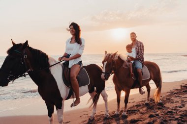 Aile kumlu bir sahilde birlikte ata binerken çocuklarıyla vakit geçirir. Seçici odaklanma. Yüksek kalite fotoğraf