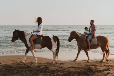 Aile kumlu bir sahilde birlikte ata binerken çocuklarıyla vakit geçirir. Seçici odaklanma. Yüksek kalite fotoğraf