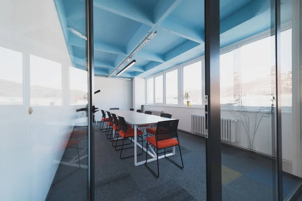 Interior of cozy light boardroom with table, modern stylish chairs and desktop computer, all ready for corporate meeting. Empty spacious office of business company or creative coworking space. Quality