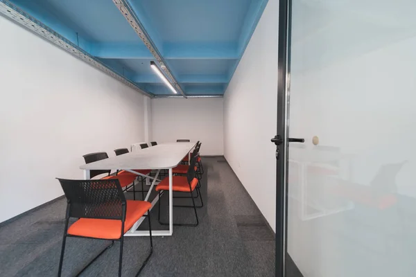 Interior of cozy light boardroom with table, modern stylish chairs and desktop computer, all ready for corporate meeting. Empty spacious office of business company or creative coworking space. Quality