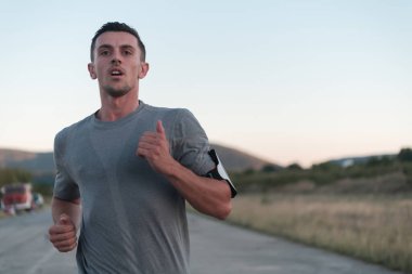 Çekici zinde bir adam gün batımında kırsal yolda hızla koşuyor, dışarıda koşuyor. Yüksek kalite fotoğraf