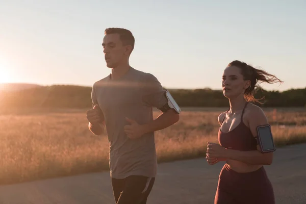 一对健康的年轻夫妇在城市街道上慢跑 背景是美丽的日出 高质量的照片 — 图库照片